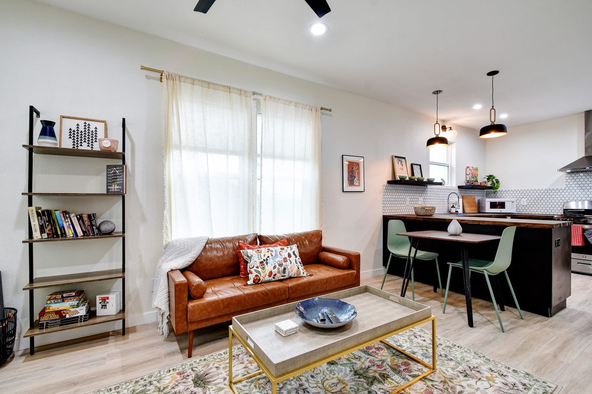 Open-plan living room with leather sofa and kitchen beyond at The Waverly – East