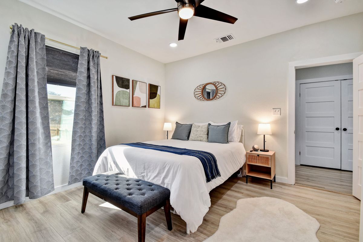 Bedroom with queen bed, upholstered bench, and blackout curtains