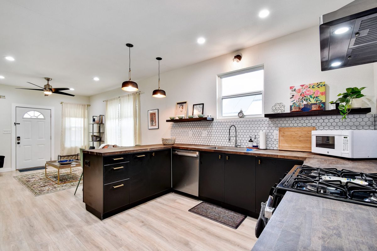 Kitchen with black cabinetry and wood counters, looking toward the front door