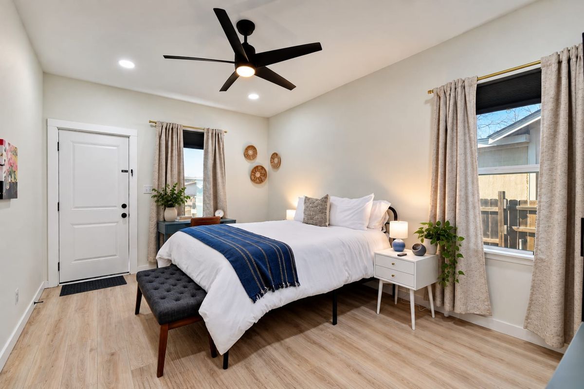 Bedroom with queen bed, bench, and door to the yard